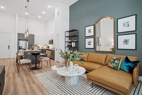 A modern living room with a brown leather couch and a dining table with chairs.
