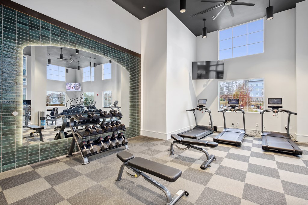 a gym with weights and a tv in a building with windows