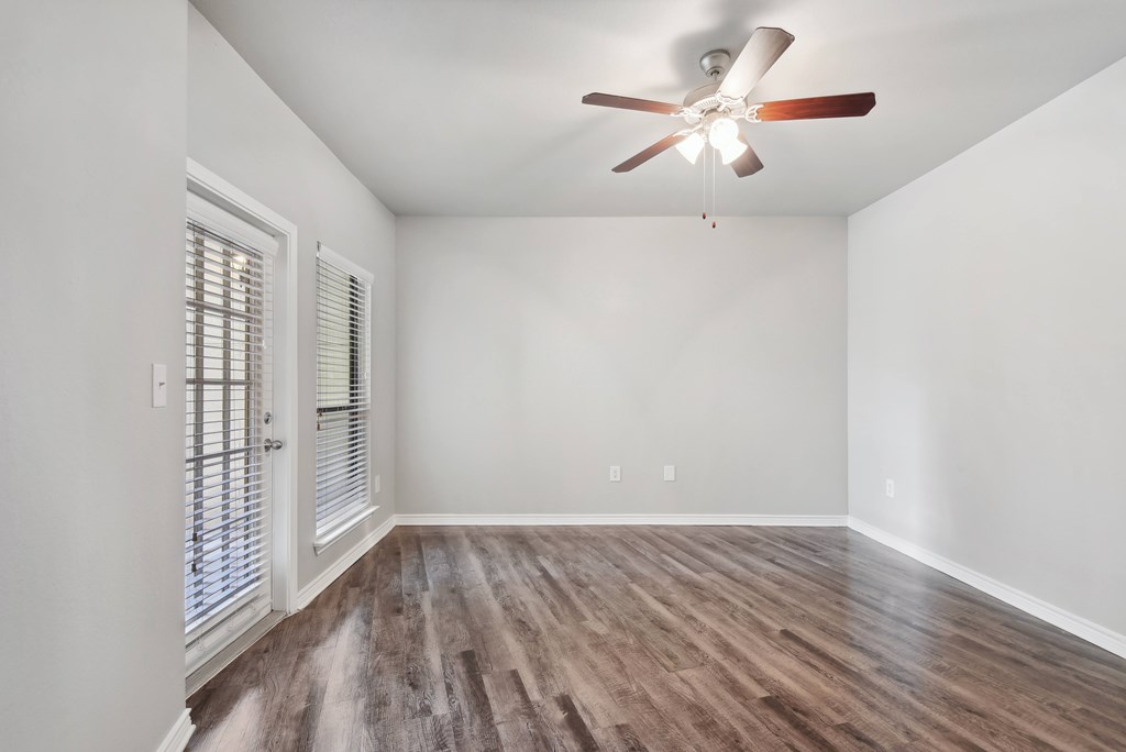 an empty living room with a ceiling fan and a window