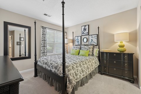 A bedroom with a four poster bed and a dresser.