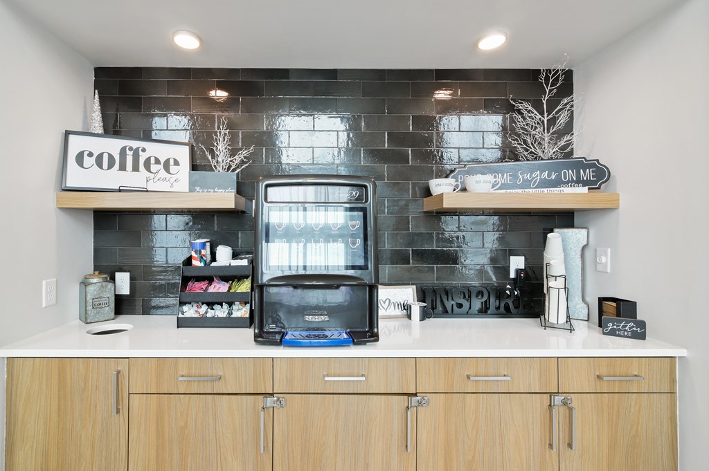 a kitchen with a coffee maker on the counter and a black brick wall