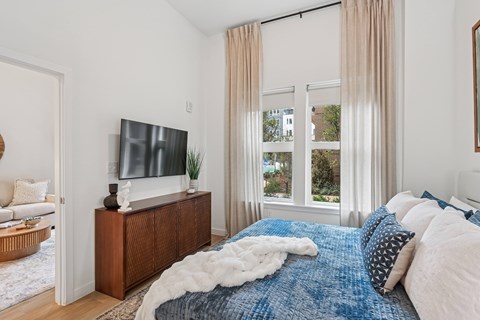 A bedroom with a large bed and a flat screen TV on a wooden stand.