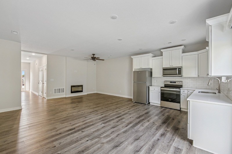 A spacious kitchen with white cabinets and a wooden floor.