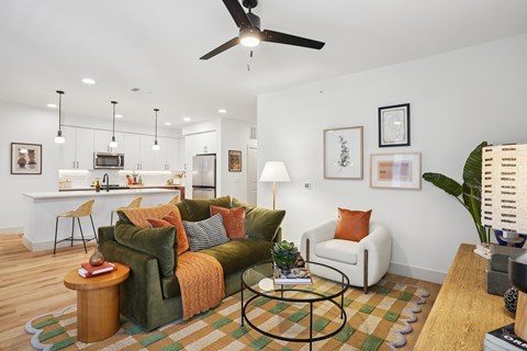 A living room with a green couch and a fan on the ceiling.