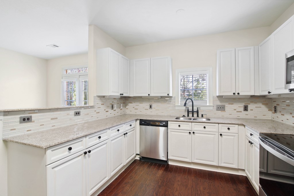 a large white kitchen with white cabinets and a stainless steel sink