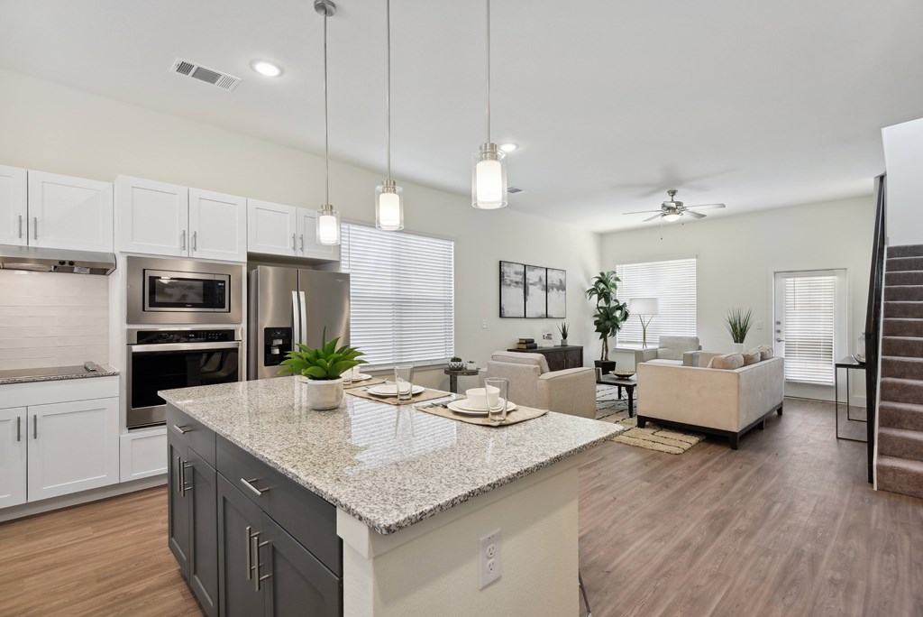 an open kitchen and living room with a granite counter top