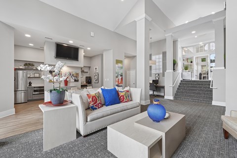 A modern living room with a white couch and a television mounted on the wall.