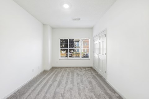 A room with a striped carpet and a window showing a view of a street.