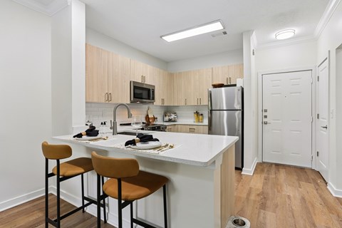 A kitchen with a white countertop and wooden cabinets.