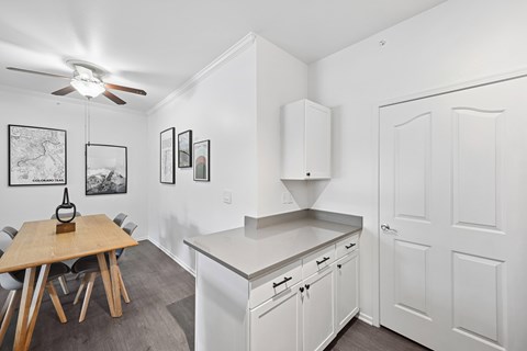 A kitchen with white cabinets and a wooden table.