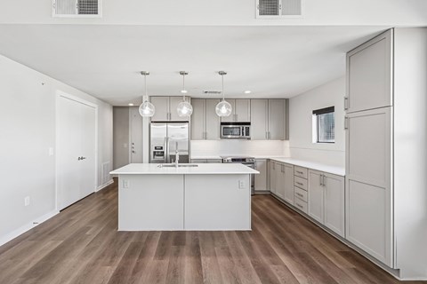 A modern kitchen with white cabinets and a wooden floor.