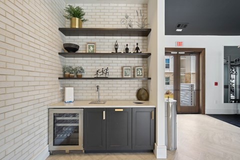 A kitchen area with a white brick wall and a black countertop with a sink and a dishwasher.