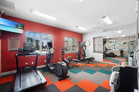 A gym with a treadmill, elliptical trainer, and other exercise equipment.