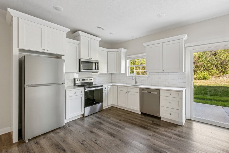 A kitchen with white cabinets and a refrigerator.