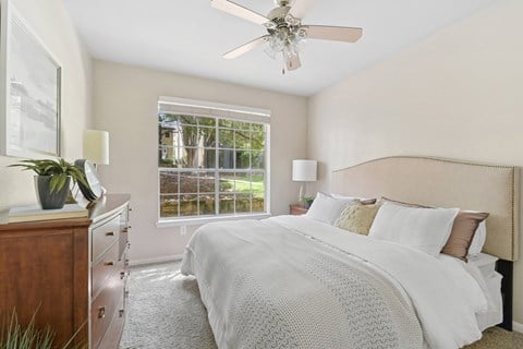 A bedroom with a large bed and a ceiling fan.