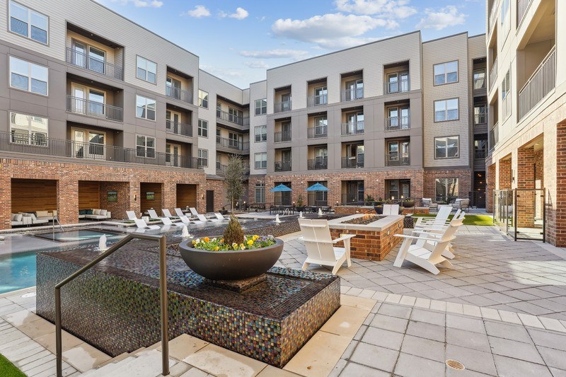 an apartment courtyard with a pool and chairs and tables