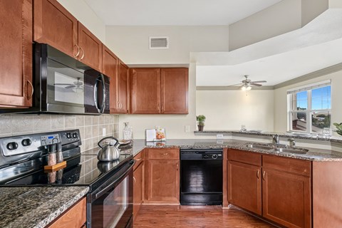 A kitchen with brown cabinets and black appliances.