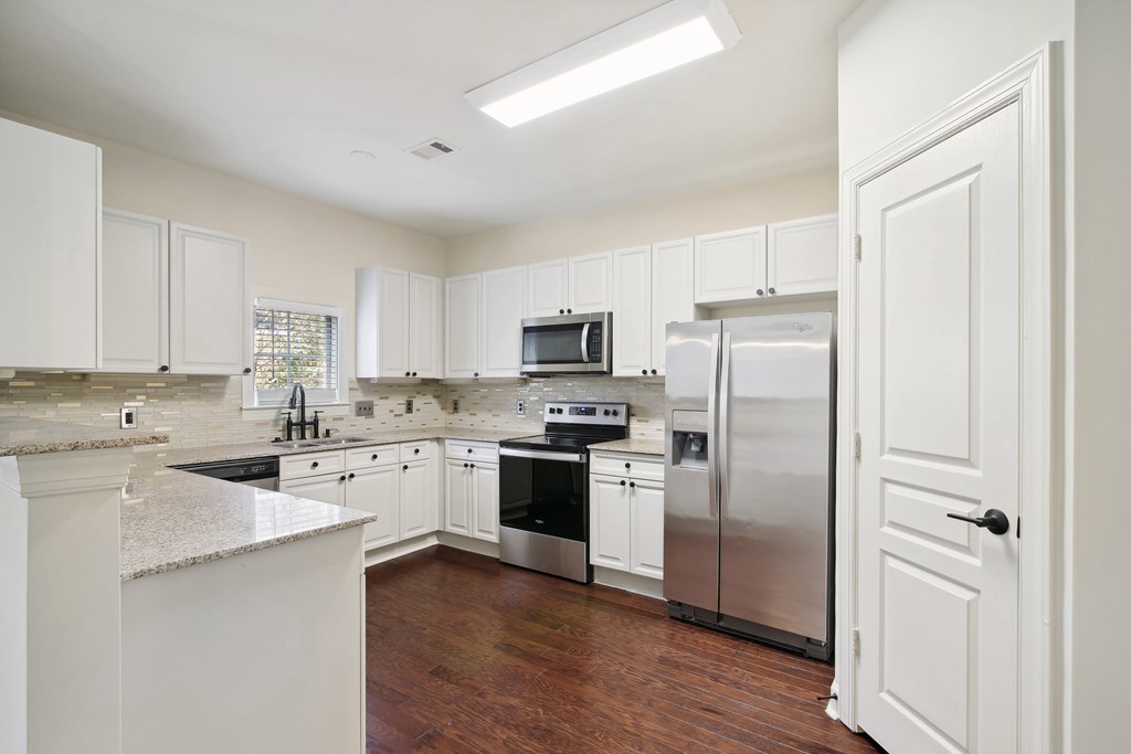 a large kitchen with white cabinets and stainless steel appliances