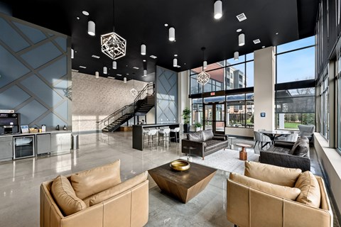 A modern living room with tan couches and a staircase in the background.