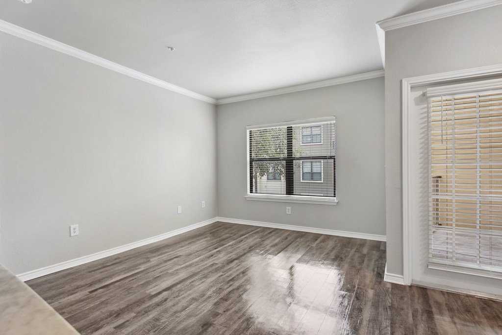 an empty living room with wood floors and a window