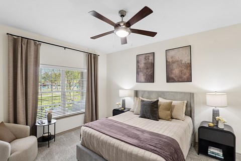 A bedroom with a bed, chair, and window.