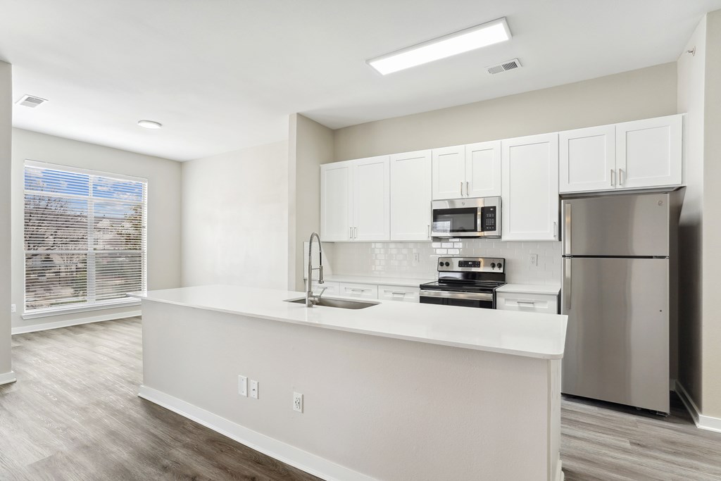 an empty kitchen with white cabinets and stainless steel appliances