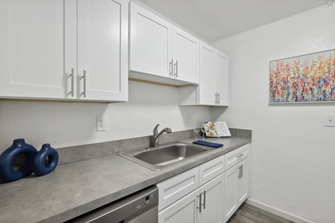 A kitchen with white cabinets and a grey countertop.