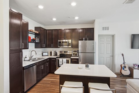 A modern kitchen with dark wood cabinets and stainless steel appliances.