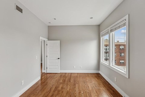 A room with a wooden floor and a window showing a building outside.