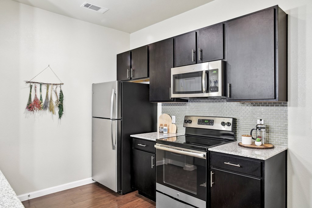 an apartment kitchen with stainless steel appliances and black cabinets