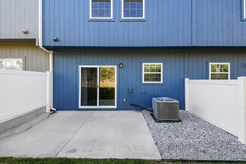 A blue house with a white fence and a grey HVAC unit.