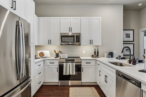 A modern kitchen with white cabinets and stainless steel appliances.