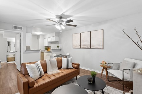 A living room with a brown couch and a ceiling fan.