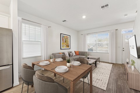 A dining room with a table set for two and a couch with a pillow.