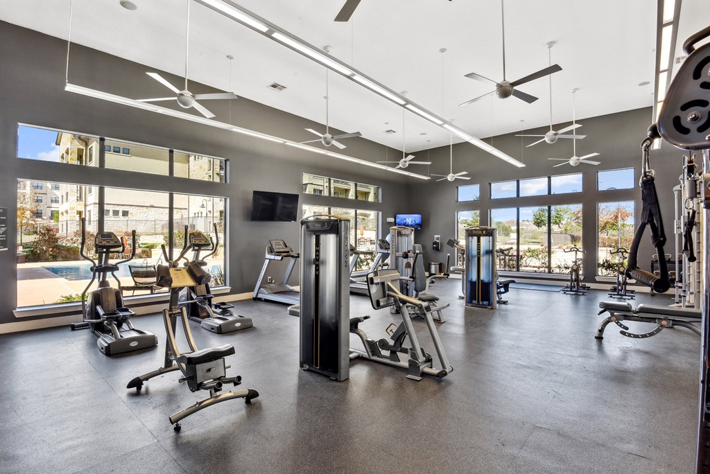a gym with weights and cardio equipment and windows
