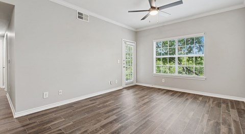 A room with a ceiling fan and a window with a view of trees.