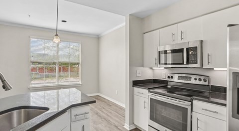 A kitchen with white cabinets and black countertops.