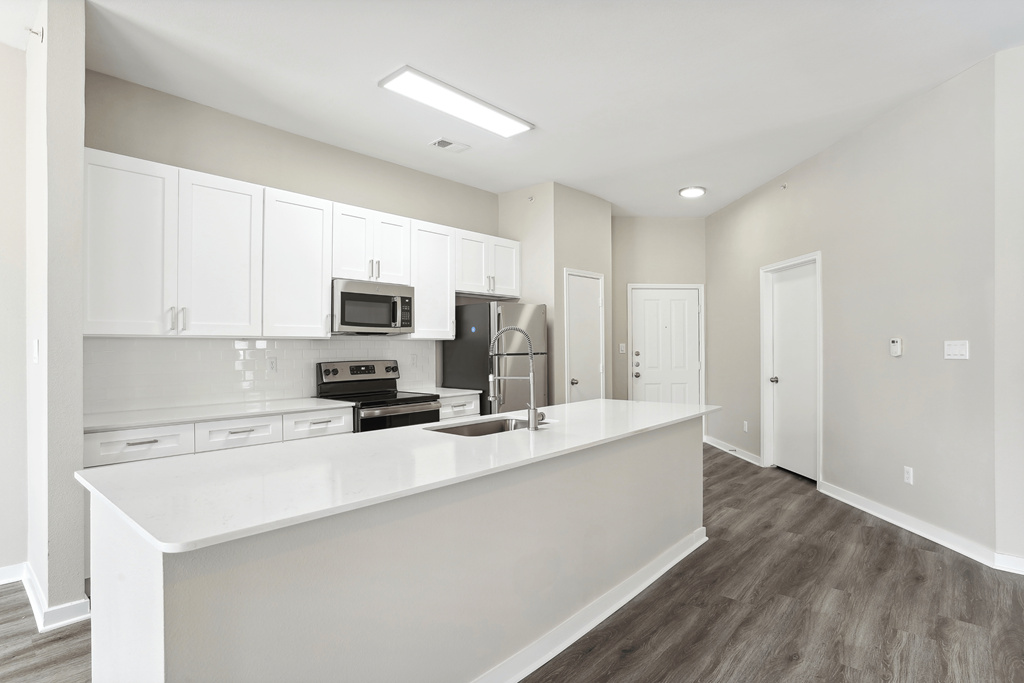 an empty kitchen with white cabinets and a white counter top