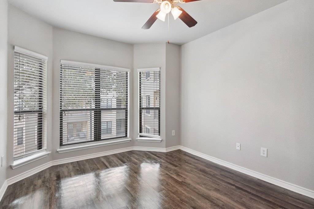 an empty living room with windows and a ceiling fan