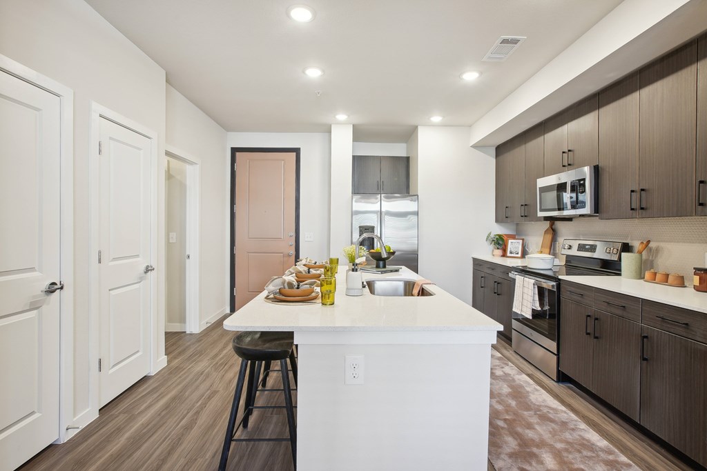an open kitchen with a large white island and stainless steel appliances