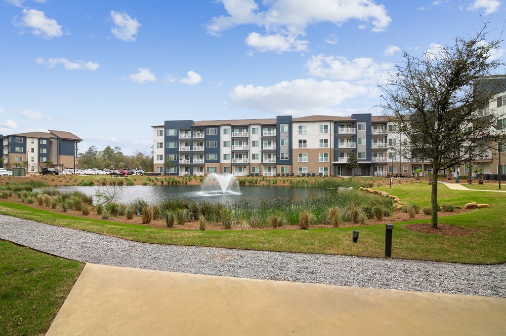 a view of a pond with a fountain in front of an apartment building