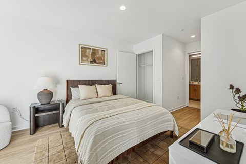A bedroom with a large bed and a nightstand with a lamp.