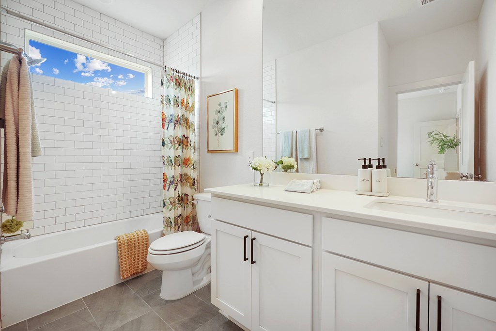 a bathroom with white cabinets and a white toilet next to a bathtub with a shower curtain
