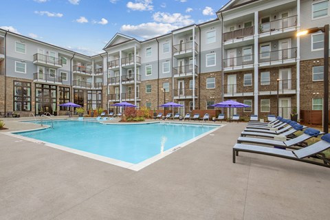 an apartment building with a swimming pool and lounge chairs