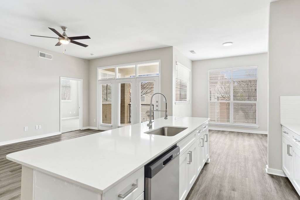 Kitchen with hardwood-style flooring, stainless steel appliances, white quartz countertops, new lighting fixtures, and white cabinetry