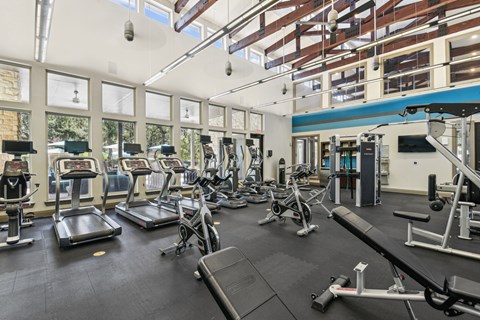 a gym with cardio equipment and windows in a building