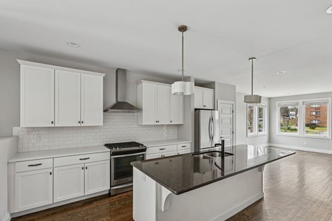 A modern kitchen with white cabinets and a black countertop.