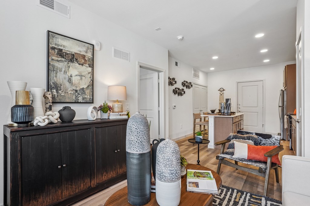 A living room with a black dresser and a painting on the wall.