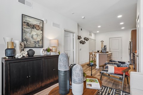 A living room with a black dresser and a painting on the wall.