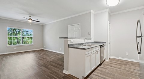 A kitchen with white cabinets and a wooden floor.